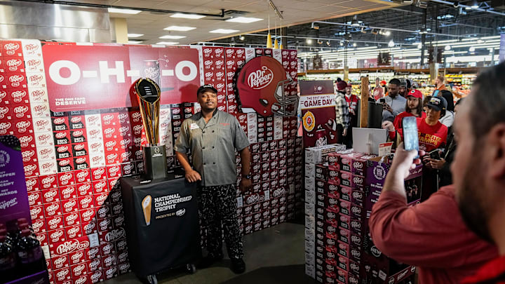Market District executive chef Kevin Andrews takes a photo with the College Football Playoff National Championship Trophy presented by Dr Pepper at the Grandview Yard grocery store on Jan. 23, 2025. The trophy is making the rounds through Columbus after the Ohio State Buckeyes defeated Notre Dame 34-23 in the championship game in Atlanta.