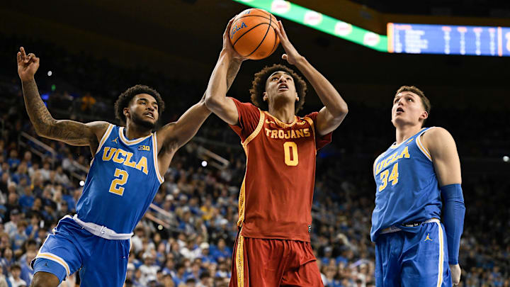 Feb 24, 2026; Los Angeles, California, USA; Southern California Trojans guard Alijah Arenas (0) drives to the basket past UCLA Bruins guard Donovan Dent (2) and forward Tyler Bilodeau (34) during the first half at Pauley Pavilion presented by Wescom Financial. Mandatory Credit: Robert Hanashiro-Imagn Images