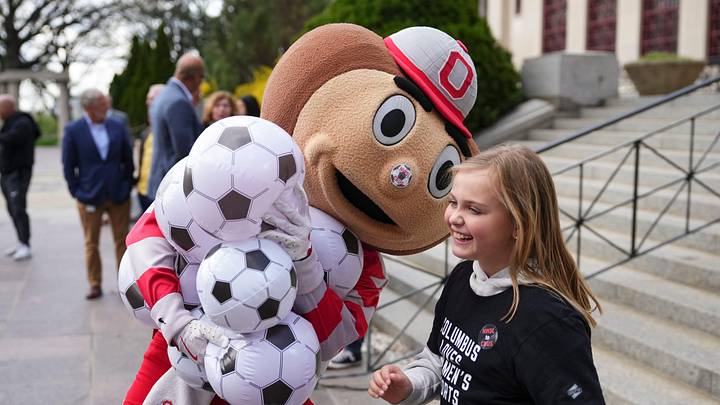 Prior to a Columbus City Council hearing about public funding for a women's professional soccer team, Charlotte Fening, 10, interacts with Brutus Buckeye as NWSL supporters rally outside Columbus City Hall on April 6, 2026. Prior to a Columbus City Council hearing about public funding for a women's professional soccer team, Charlotte Fening, 10, interacts with Brutus Buckeye as NWSL supporters rally outside Columbus City Hall on April 6, 2026.