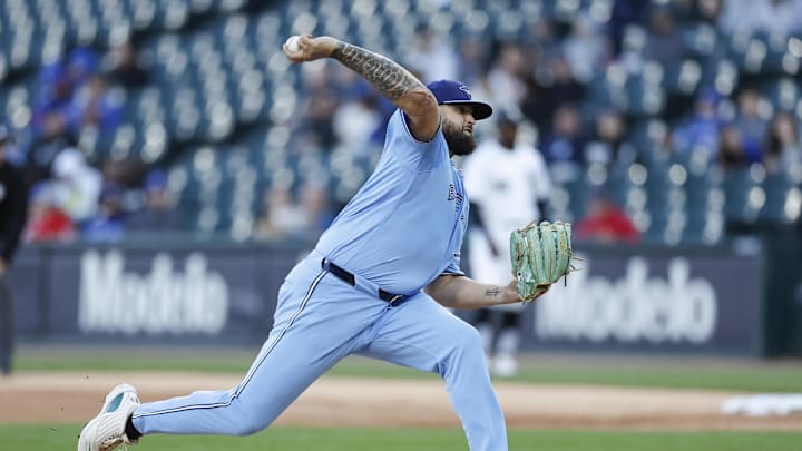 A baseball player in a blue uniform pitching a white baseball while wearing a blue hat