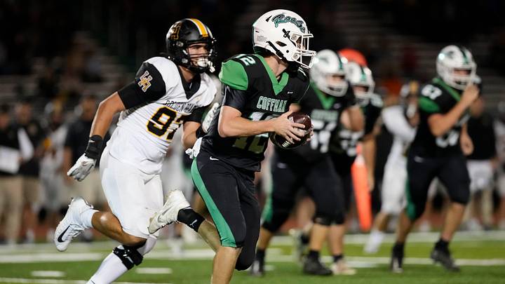 Oct 13, 2023; Dublin, Ohio, USA; Dublin Coffman quarterback Quinn Hart (12) scrambles away from Upper Arlington defensive lineman Cal Thrush (97) during the high school football game at Dublin Coffman.