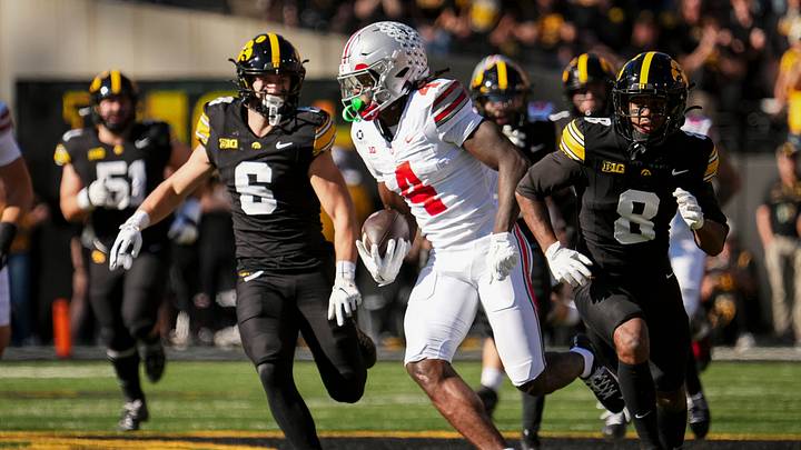 Ohio State Buckeyes wide receiver Jeremiah Smith (4) runs past Iowa Hawkeyes defensive back Zach Lutmer (6) and defensive back Deshaun Lee (8) after making a catch during the NCAA football game at Kinnick Stadium in Iowa City on Oct. 3, 2026.