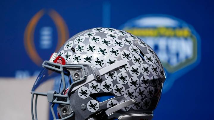 An Ohio State Buckeyes helmet sits in the desk in front of head coach Ryan Day as he talks to media during a Cotton Bowl press conference at AT&T Stadium in Arlington, Texas prior to their College Football Playoff quarterfinal matchup on Dec. 30, 2025.