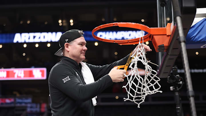 Mar 14, 2026; Kansas City, MO, USA; Arizona Wildcats head coach Tommy Lloyd cuts the net after a win over the Houston Cougars during the men's Big 12 Conference Tournament Championship at T-Mobile Center. Mandatory Credit: William Purnell-Imagn Images