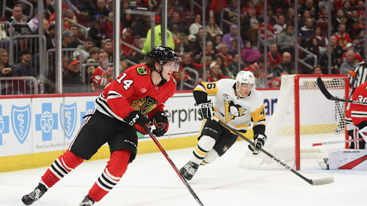 Apr 6, 2025; Chicago, Illinois, USA; Chicago Blackhawks defenseman Kevin Korchinski (14) skates with the puck against the Pittsburgh Penguins during the second period at United Center. Mandatory Credit: Talia Sprague-Imagn Images
