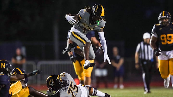 American Heritage Patriots receiver Malachi Toney (1) hurdles lineman Dayen Araibi (75) after catching a pass during the first quarter of a game against the Naples Golden Eagles at Staver Field in Naples on Friday, Sept. 13, 2024.