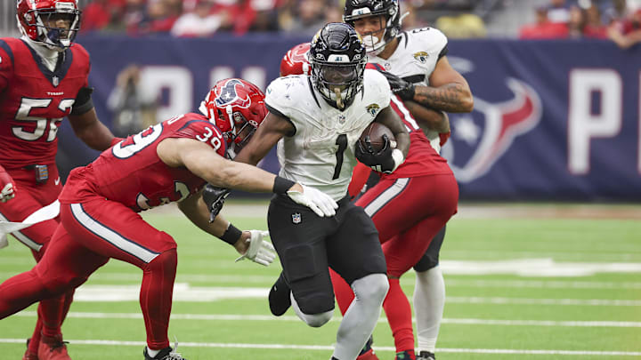 Nov 26, 2023; Houston, Texas, USA; Jacksonville Jaguars running back Travis Etienne Jr. (1) runs with the ball as Houston Texans linebacker Henry To'oTo'o (39) attempts to make a tackle during the fourth quarter at NRG Stadium. Mandatory Credit: Troy Taormina-Imagn Images