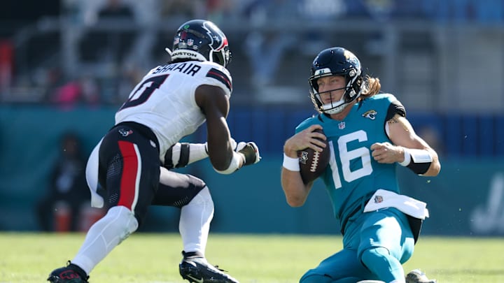 Dec 1, 2024; Jacksonville, Florida, USA; Jacksonville Jaguars quarterback Trevor Lawrence (16) slides down in front of Houston Texans linebacker Azeez Al-Shaair (0) in the second quarter in the second quarter at EverBank Stadium. Mandatory Credit: Nathan Ray Seebeck-Imagn Images