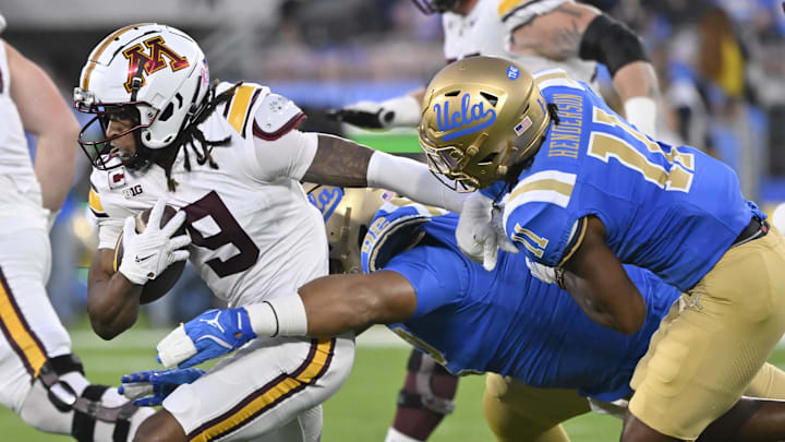 Oct 12, 2024; Pasadena, California, USA; Minnesota Golden Gophers wide receiver Daniel Jackson (9) tries to run against UCLA Bruins defensive lineman Siale Taupaki (92) and defensive back Ramon Henderson (11) during the first quarter at Rose Bowl. Mandatory Credit: Robert Hanashiro-Imagn Images