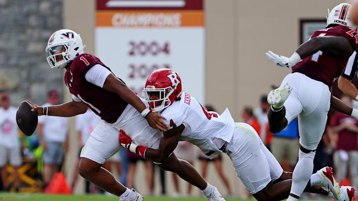 Sep 21, 2024; Blacksburg, Virginia, USA; Virginia Tech Hokies quarterback Kyron Drones (1) is pressed by Rutgers Scarlet Knights defensive back Desmond Igbinosun (4) during the second quarter at Lane Stadium. Mandatory Credit: Peter Casey-Imagn Images