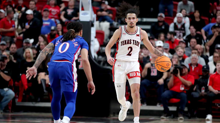 Jan 3, 2023; Lubbock, Texas, USA;  Texas Tech Red Raiders guard Pop Issacs (2) brings the ball up court against Kansas Jayhawks guard Bobby Pettiford Jr (0) in the first half at United Supermarkets Arena. Mandatory Credit: Michael C. Johnson-Imagn Images