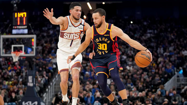Jan 31, 2025; San Francisco, California, USA; Golden State Warriors guard Stephen Curry (30) dribbles the ball in front of Phoenix Suns guard Devin Booker (1) in the fourth quarter at the Chase Center. Mandatory Credit: Cary Edmondson-Imagn Images