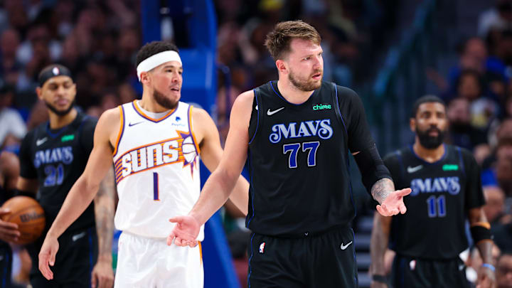 Feb 22, 2024; Dallas, Texas, USA; Dallas Mavericks guard Luka Doncic (77) reacts in front of Phoenix Suns guard Devin Booker (1) during the first half at American Airlines Center. Mandatory Credit: Kevin Jairaj-Imagn Images