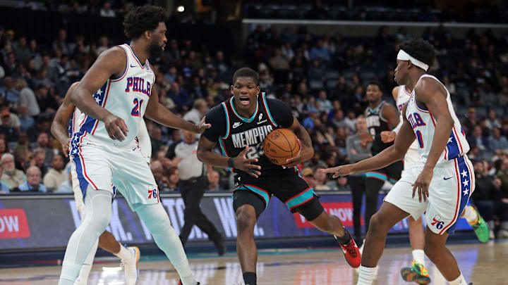 Dec 30, 2025; Memphis, Tennessee, USA; Memphis Grizzlies forward Cedric Coward (23) drives to the basket between Philadelphia 76ers center Joel Embiid (21) and guard VJ Edgecombe (77) during the third quarter at FedExForum. Mandatory Credit: Petre Thomas-Imagn Images