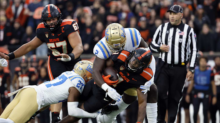 Oct 14, 2023; Corvallis, Oregon, USA; Oregon State Beavers running back Deshaun Fenwick (1) is tackled by UCLA Bruins defensive back Kamari Ramsey (27) and linebacker Oluwafemi Oladejo (2) during the first half at Reser Stadium. Mandatory Credit: Soobum Im-Imagn Images