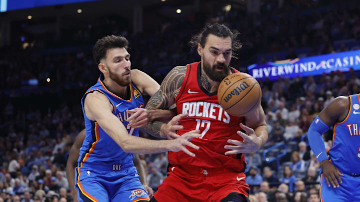 Oct 21, 2025; Oklahoma City, Oklahoma, USA; Houston Rockets center Steven Adams (12) and Oklahoma City Thunder center Chet Holmgren (7) reach for a loose ball during the second half at Paycom Center. Mandatory Credit: Alonzo Adams-Imagn Images