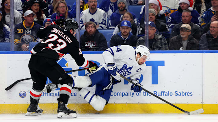 Dec 20, 2024; Buffalo, New York, USA;  Buffalo Sabres defenseman Mattias Samuelsson (23) checks Toronto Maple Leafs center Auston Matthews (34) as he goes for the puck during the first period at KeyBank Center. Mandatory Credit: Timothy T. Ludwig-Imagn Images