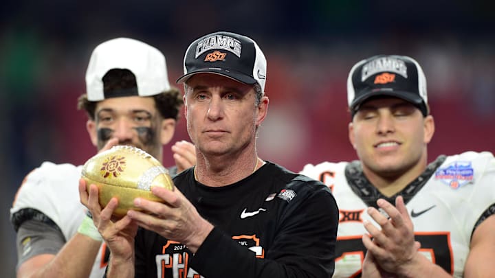 Jan 1, 2022; Glendale, Arizona, USA; Oklahoma State Cowboys head coach Mike Gundy celebrates with the trophy after defeating the Notre Dame Fighting Irish in the 2022 Fiesta Bowl at State Farm Stadium. Mandatory Credit: Joe Camporeale-Imagn Images