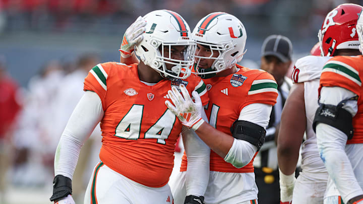 Dec 28, 2023; Bronx, NY, USA; Miami Hurricanes defensive lineman Rueben Bain Jr. (44) and linebacker Francisco Mauigoa (51) celebrates after a defensive stop during the first half of the 2023 Pinstripe Bowl against the Rutgers Scarlet Knights at Yankee Stadium. Mandatory Credit: Vincent Carchietta-Imagn Images