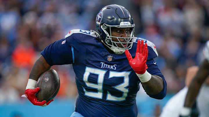 Tennessee Titans defensive tackle T'Vondre Sweat returns the ball after stripping it from Cincinnati Bengals quarterback Joe Burrow.