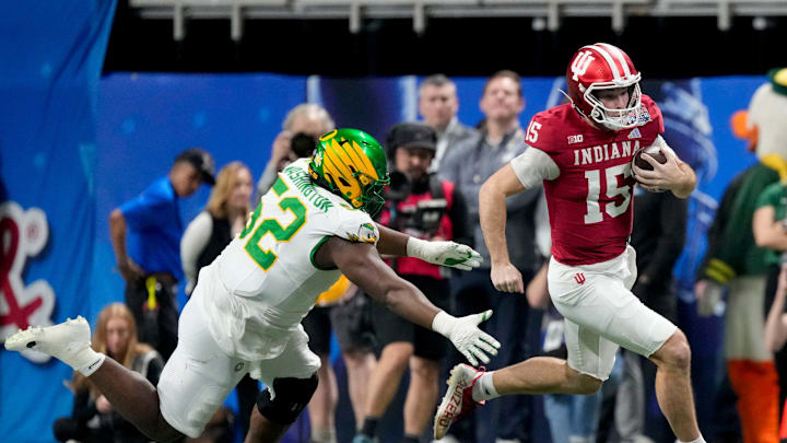 Indiana Hoosiers quarterback Fernando Mendoza (15) rushes the ball as Oregon Ducks defensive lineman A'mauri Washington (52) gives chase Friday, Jan. 9, 2026, during the Peach Bowl and semifinal game of the College Football Playoff at Mercedes-Benz Stadium in Atlanta. Indiana Hoosiers quarterback Fernando Mendoza (15) rushes the ball as Oregon Ducks defensive lineman A'mauri Washington (52) gives chase Friday, Jan. 9, 2026, during the Peach Bowl and semifinal game of the College Football Playoff at Mercedes-Benz Stadium in Atlanta.