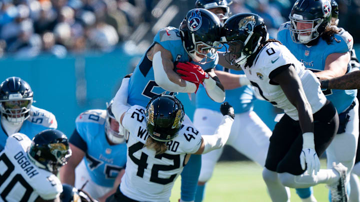 Tennessee running back Tony Pollard (20) is tackled by Jacksonville safety Andrew Wingard (42) and linebacker Devin Eric Lloyd (0) during their game at Nissan Stadium Sunday, Nov. 30, 2025.
