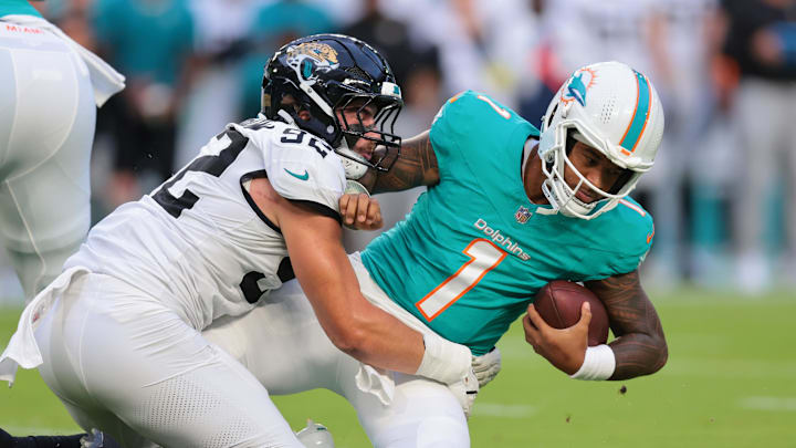 Aug 23, 2025; Miami Gardens, Florida, USA; Jacksonville Jaguars defensive end Danny Striggow (92) tackles Miami Dolphins quarterback Tua Tagovailoa (1) during the first quarter at Hard Rock Stadium. Mandatory Credit: Sam Navarro-Imagn Images