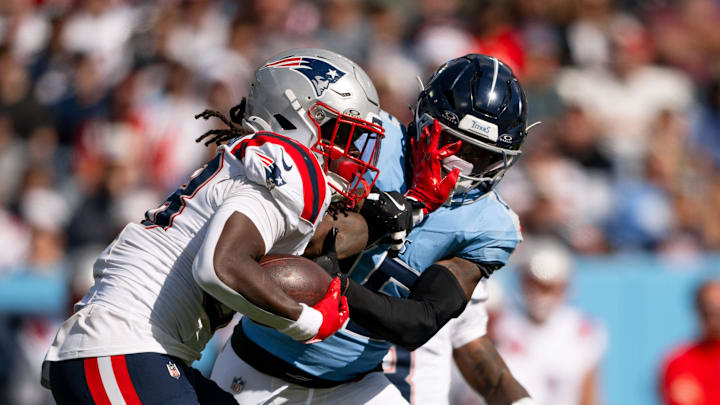New England Patriots running back Rhamondre Stevenson stiff arms Tennessee Titans safety Xavier Woods.