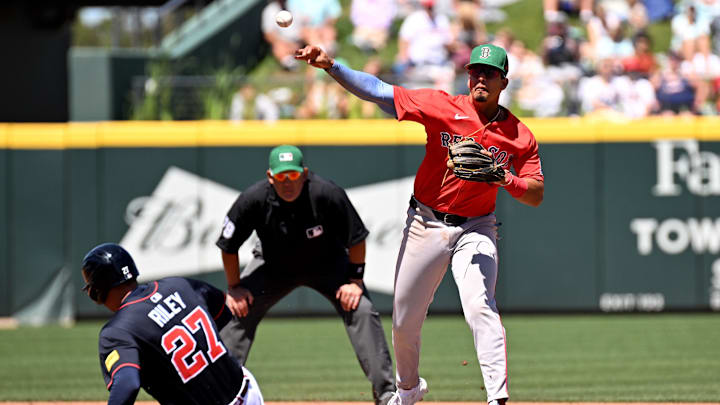 Mar 17, 2025; North Port, Florida, USA; Atlanta Braves third baseman Austin Riley (27) slides as Boston Red Sox second baseman Vaughn Grissom (5) throws to first base in the fourth inning during spring training at CoolToday Park. Mandatory Credit: Jonathan Dyer-Imagn Images