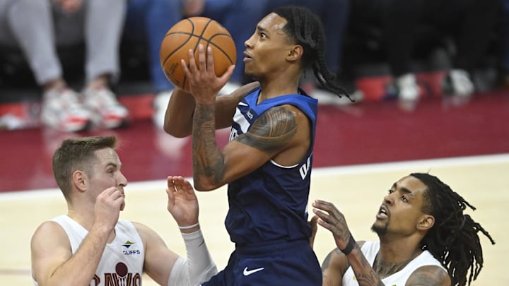 Feb 10, 2025; Cleveland, Ohio, USA; Minnesota Timberwolves guard Rob Dillingham (4) drives between Cleveland Cavaliers guard Sam Merrill (5) and forward Emoni Bates (21) in the fourth quarter at Rocket Mortgage FieldHouse. Mandatory Credit: David Richard-Imagn Images