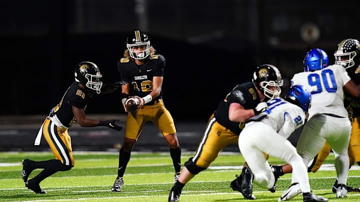 Oct 20, 2023; Carrollton, GA, USA; Carrollton Trojans quarterback Julian Lewis (10) hands-off against the Westlake Lions during the first half at Grisham Stadium. The 15-year-old Carrollton High student has already committed to playing for the University of Southern California Trojans and has been considered one of the top high school quarterback prospects. Mandatory Credit: John David Mercer-Imagn Images