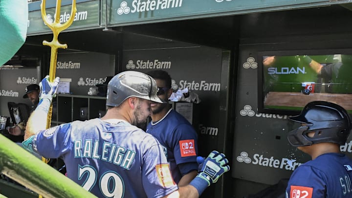 Seattle Mariners catcher Cal Raleigh (29) celebrates in the dugout with outfielder Julio RodrÌguez (44) and  first baseman Donovan Solano (39) after he hits a home run against the Chicago Cubs during the first inning at Wrigley Field on June 20. 