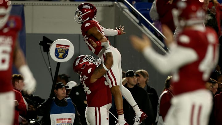 Dec 27, 2024; Memphis, TN, USA; Arkansas Razorbacks quarterback Taylen Green (10) is lifted by offensive linemen Keyshawn Blackstock (54) after a touchdown during the first quarter against the Texas Tech Red Raiders at Simmons Bank Liberty Stadium. Mandatory Credit: Petre Thomas-Imagn Images