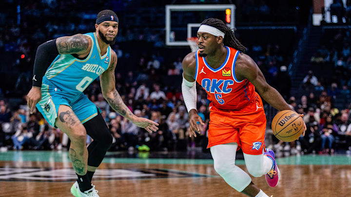 Apr 7, 2024; Charlotte, North Carolina, USA; Oklahoma City Thunder guard Luguentz Dort (5) drives by Charlotte Hornets forward Miles Bridges (0) during the first quarter at Spectrum Center. Mandatory Credit: Scott Kinser-Imagn Images