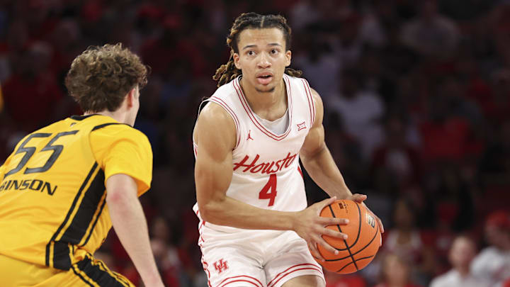 Nov 12, 2025; Houston, Texas, USA; Houston Cougars guard Kingston Flemings (4) controls the ball as Oakland Golden Grizzlies guard Brody Robinson (55) defends during the first half at Fertitta Center.