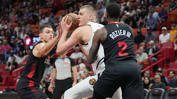 Mar 13, 2024; Miami, Florida, USA;  Denver Nuggets center Nikola Jokic (15) drives to the basket as Miami Heat guard Terry Rozier (2) and Miami Heat forward Nikola Jovic (5), right, defend during the first half at Kaseya Center. Mandatory Credit: Jim Rassol-Imagn Images