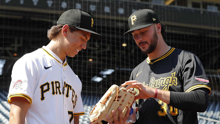 Jul 22, 2025; Pittsburgh, Pennsylvania, USA;  Seth Hernandez (left) the Pittsburgh Pirates first round and number six overall pick in the 2025 first year player draft looks at the glove of Pirates pitcher Paul Skenes (30) before the game against the Detroit Tigers at PNC Park. Mandatory Credit: Charles LeClaire-Imagn Images
