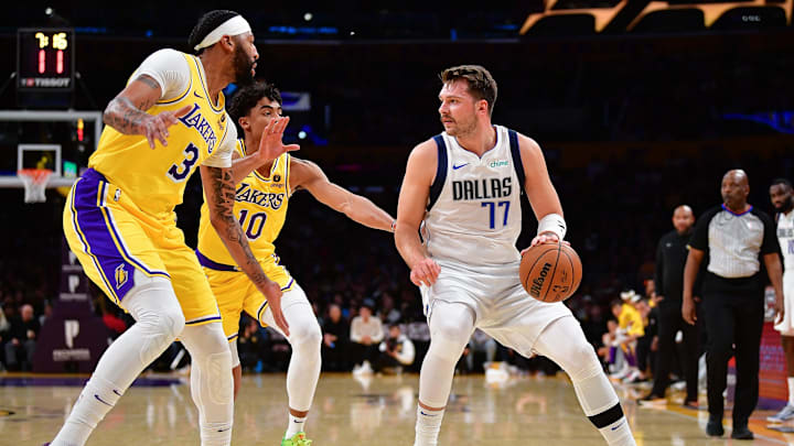 Nov 22, 2023; Los Angeles, California, USA; Dallas Mavericks guard Luka Doncic (77) moves the ball against Los Angeles Lakers forward Anthony Davis (3) and guard Max Christie (10) during the first half at Crypto.com Arena. Mandatory Credit: Gary A. Vasquez-Imagn Images