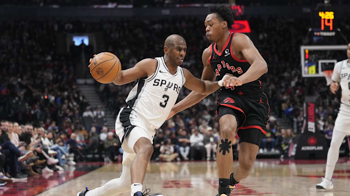 Mar 23, 2025; Toronto, Ontario, CAN; San Antonio Spurs guard Chris Paul (3) drives to the net against Toronto Raptors guard Scottie Barnes (4) during the second half at Scotiabank Arena. Mandatory Credit: John E. Sokolowski-Imagn Images