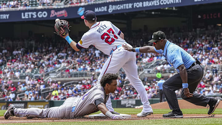 Jun 15, 2025; Cumberland, Georgia, USA; Colorado Rockies shortstop Ryan Ritter (8) slides under third baseman Austin Riley (27) after a throwing error by Atlanta Braves starting pitcher Grant Holmes (66) (not shown) during the third inning at Truist Park. Mandatory Credit: Dale Zanine-Imagn Images