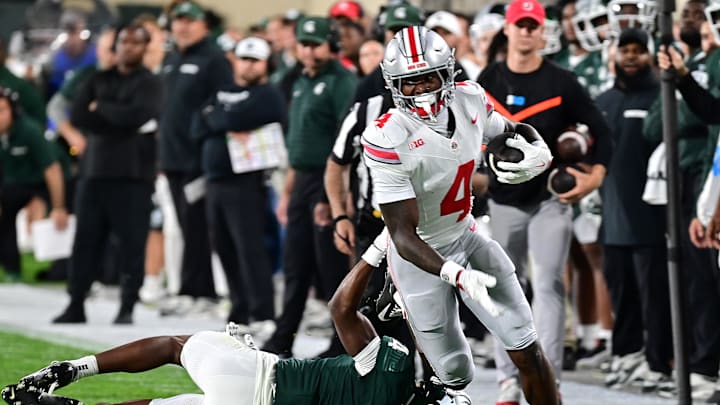 Sep 28, 2024; East Lansing, Michigan, USA;  Ohio State Buckeyes wide receiver Jeremiah Smith (4) runs past Michigan State Spartans defensive back Ed Woods (4) in the first quarter at Spartan Stadium. Mandatory Credit: Dale Young-Imagn Images
