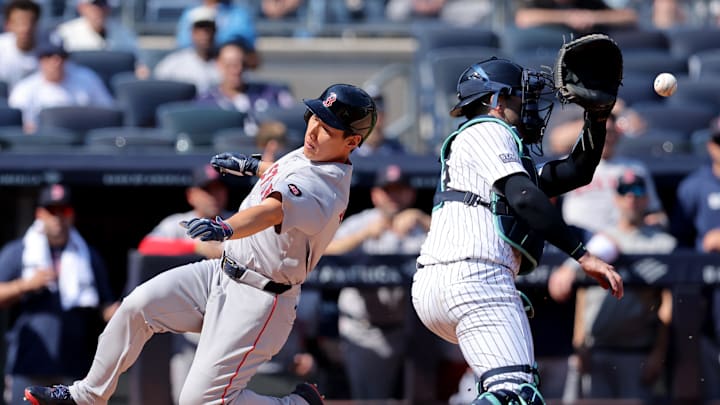 Boston Red Sox designated hitter Masataka Yoshida (7) scores a run against New York Yankees catcher Austin Wells (28) on an RBI single by Red Sox right fielder Wilyer Abreu (not pictured) during the fourth inning at Yankee Stadium in 2024.