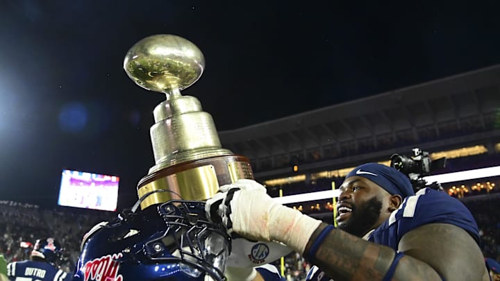 Nov 29, 2024; Oxford, Mississippi, USA; Mississippi Rebels players react with the Egg Bowl trophy after the game against the Mississippi State Bulldogs at Vaught-Hemingway Stadium. Mandatory Credit: Matt Bush-Imagn Images