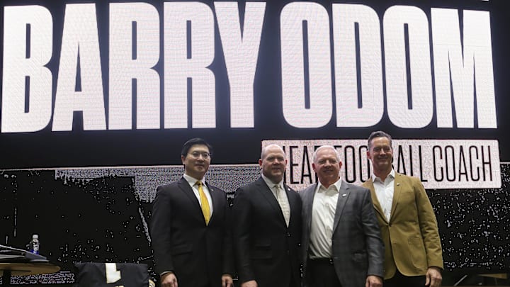 President of Purdue University Mung Chiang, Purdue football head coach Barry Odom, Purdue athletic director Mike Bobinski and Purdue Board of Trustees chair Michael Berghoff pose for a photo Tuesday, Dec. 10, 2024, during the welcoming of Purdue football head coach Barry Odom at Mackey Arena in West Lafayette, Ind.