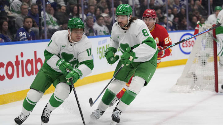 Mar 17, 2025; Toronto, Ontario, CAN; Toronto Maple Leafs forward Max Domi (11) gets control of the puck as  defenceman Chris Tanev (8) blocks out Calgary Flames forward Blake Coleman (20) during the second period at Scotiabank Arena. Mandatory Credit: John E. Sokolowski-Imagn Images