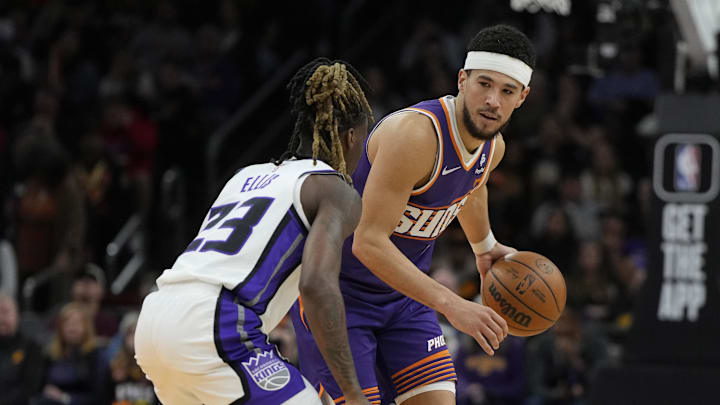 Feb 13, 2024; Phoenix, Arizona, USA; Phoenix Suns guard Devin Booker (1) drives on Sacramento Kings guard Keon Ellis (23) in the first half at Footprint Center. Mandatory Credit: Rick Scuteri-Imagn Images