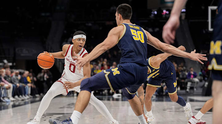 Dec 18, 2024; Charlotte, North Carolina, USA; Oklahoma Sooners guard Jeremiah Fears (0) tries to get past Michigan Wolverines center Vladislav Goldin (50) during the first half at Spectrum Center. Mandatory Credit: Jim Dedmon-Imagn Images