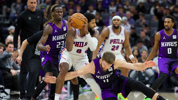 Jan 1, 2025; Sacramento, California, USA; Philadelphia 76ers forward Paul George (8) is defended by Sacramento Kings guard Keon Ellis (23) and forward Domantas Sabonis (11) during the fourth quarter at Golden 1 Center. Mandatory Credit: Sergio Estrada-Imagn Images