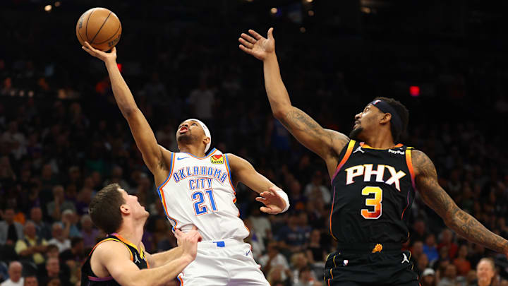 Apr 9, 2025; Phoenix, Arizona, USA; Oklahoma City Thunder guard Aaron Wiggins (21) shoots the ball over Phoenix Suns guard Collin Gillespie (12) and guard Bradley Beal (3) during the second half at Footprint Center. Mandatory Credit: Mark J. Rebilas-Imagn Images