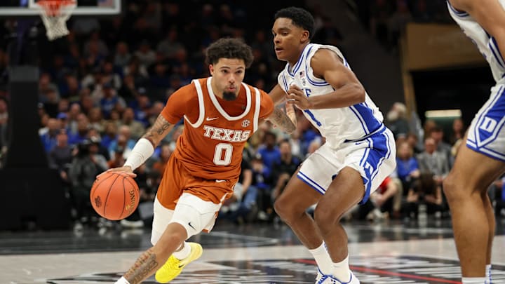 Nov 4, 2025; Charlotte, North Carolina, USA; Texas Longhorns guard Jordan Pope (0) drives the ball around Duke Blue Devils guard Caleb Foster (1) during the second half of the Dick Vitale’s Invitational game at Spectrum Center. Mandatory Credit: Cory Knowlton-Imagn Images